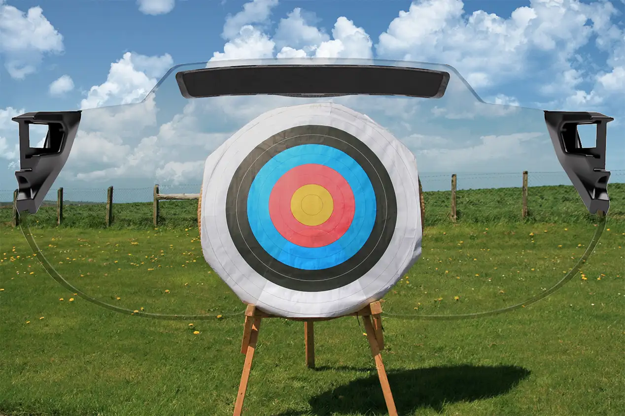 Montage capturing a full archery target with full colour archery face on a straw boss set against a green field with clear blue skies in the background. Superimposed on top is the X Sight lens from behind, providing a visual representation of how the target appears through the lens color. In this case the lens colour being represented is Clear.
